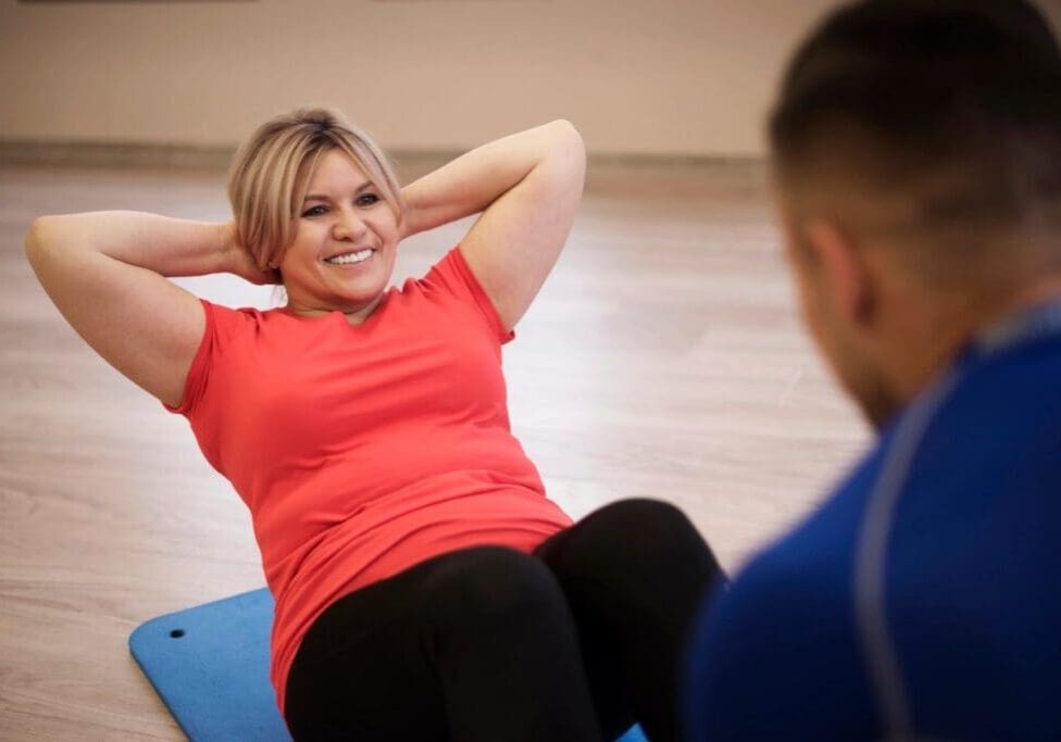 Smiling woman doing sit-ups on exercise mat