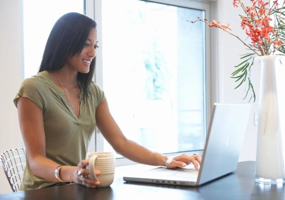 A woman sitting at a table with a laptop.