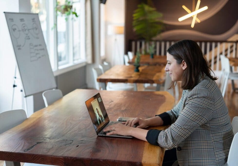 A woman sitting at a table with her laptop.